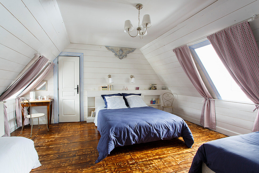 Rustic attic bedroom with white wood-clad walls