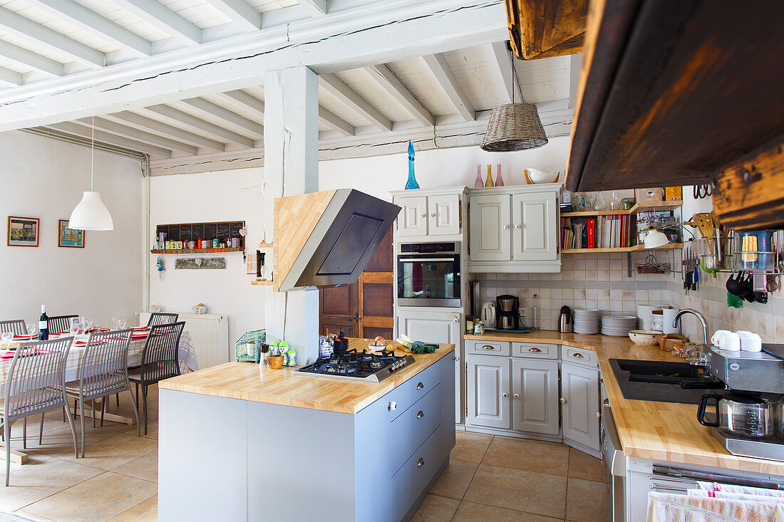 Open-plan country-house kitchen and dining area with wood-beamed ceiling