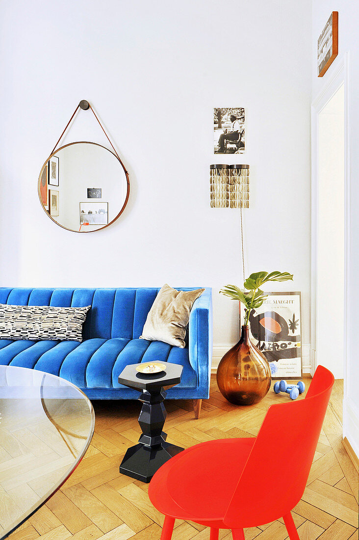Glass table, red chair and blue couch in living room