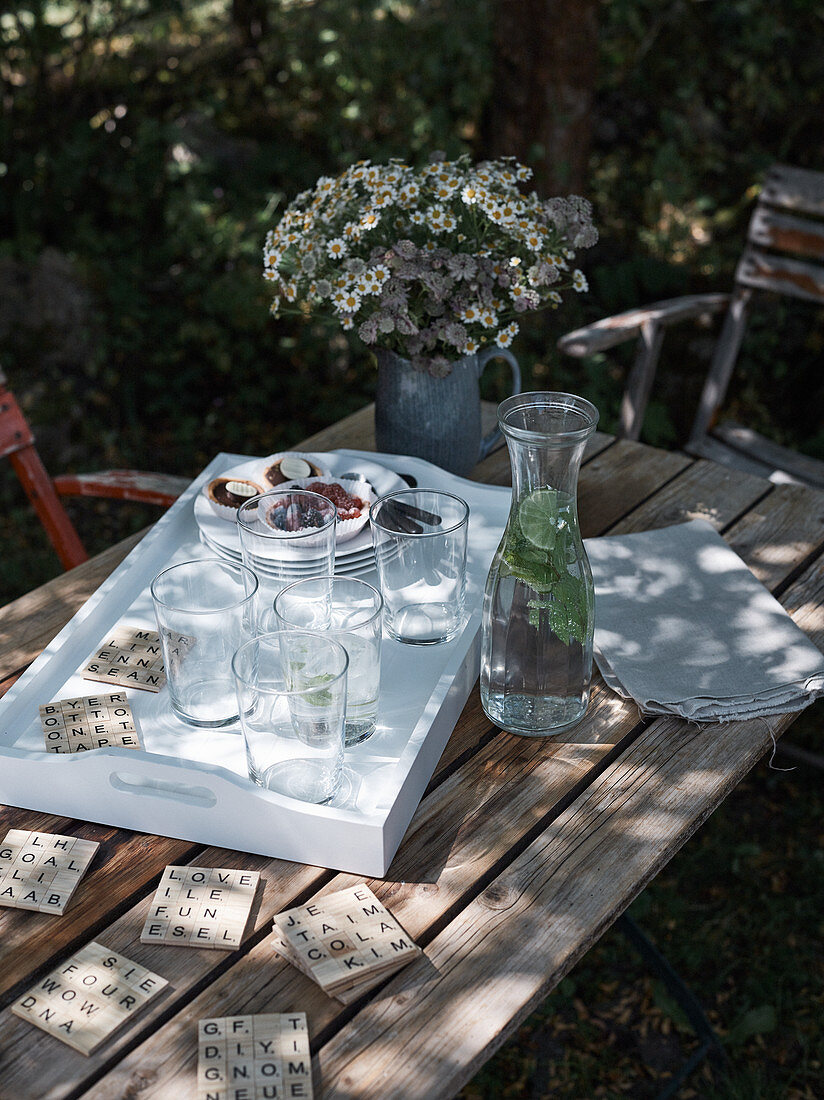 DIY-Scrabble-Coaster und Holztablett mit Gläsern auf Gartentisch