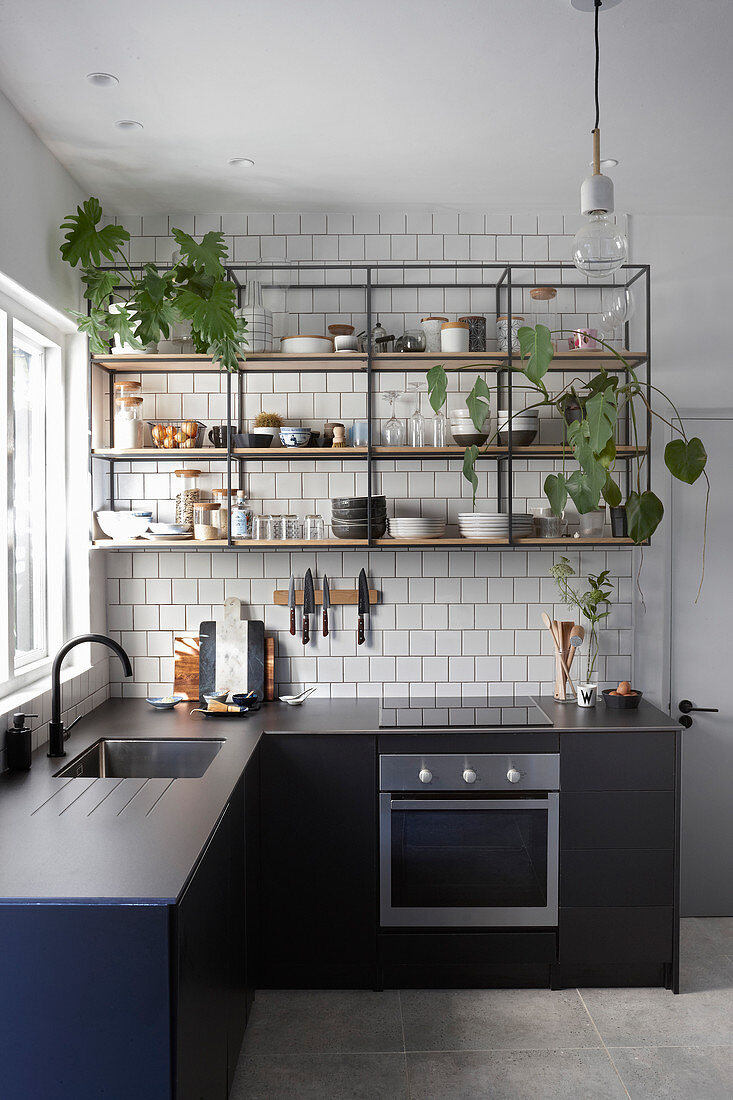 Steel and wood shelves on white-tiled wall in kitchen