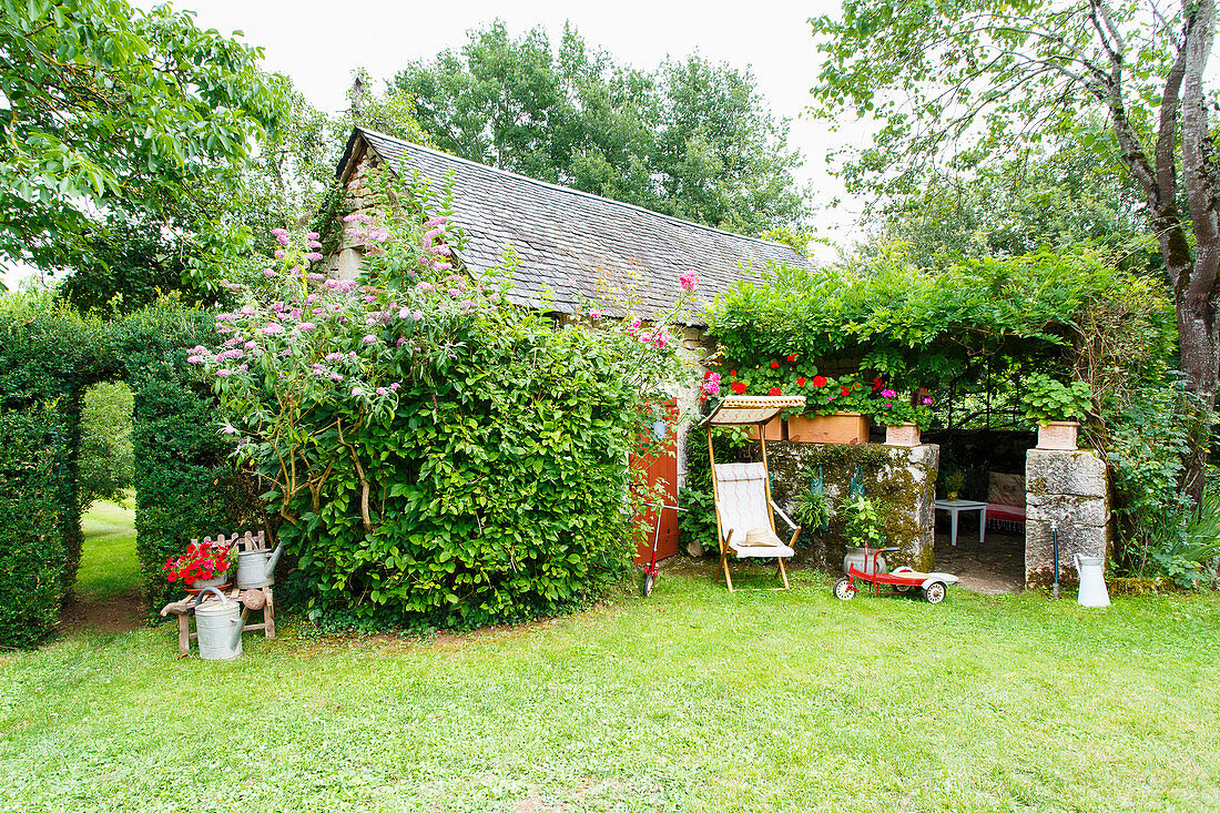 Idyllischer Garten mit einer alten Scheune und überdachtem Sitzplatz