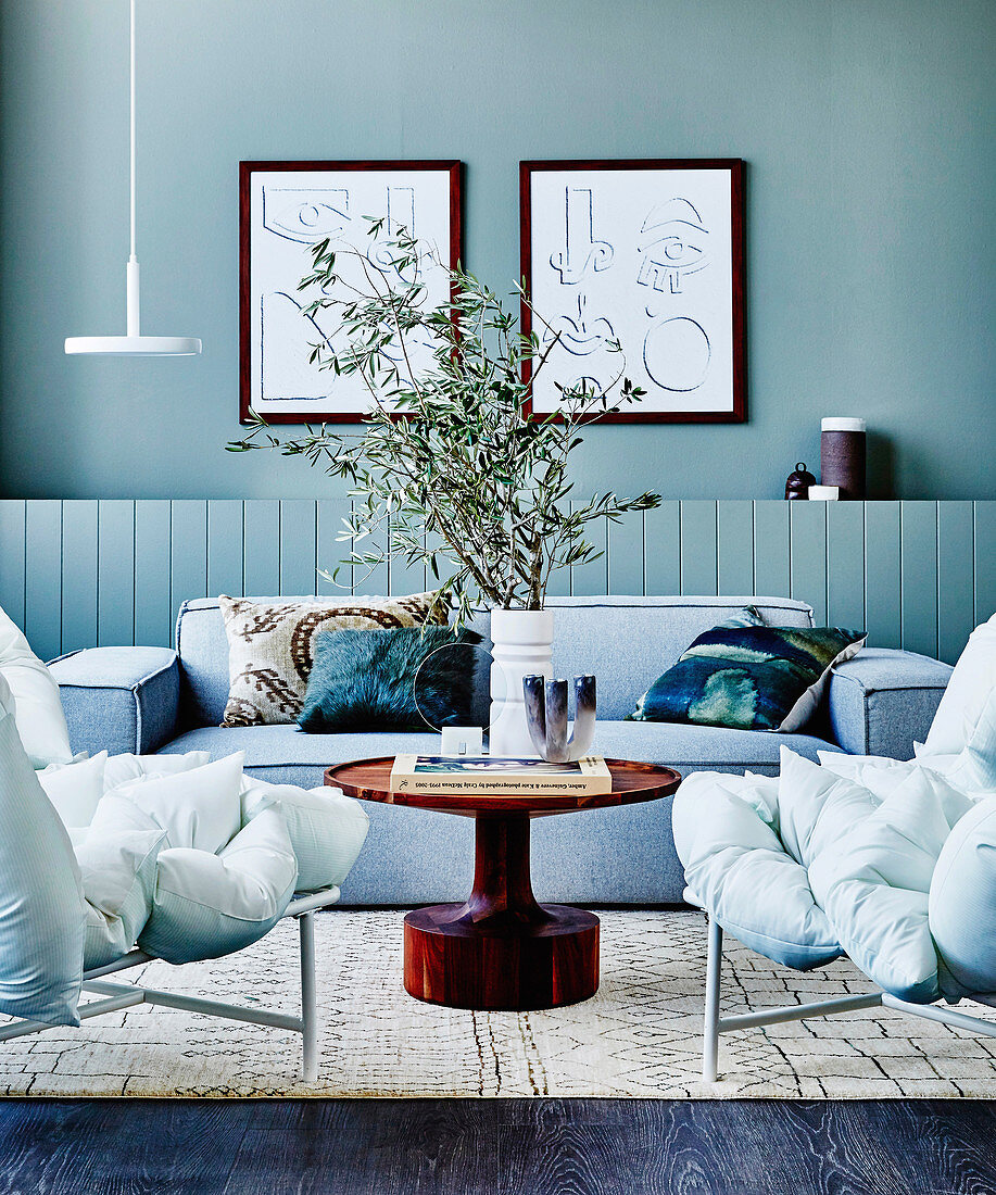 Graue Polstersofa, runder Couchtisch und geteiltes Kissen-Sofa im Wohnzimmer mit grau-grüner Wand