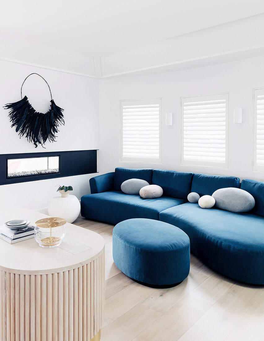 Blaue Sofagarnitur mit Polsterhocker in hellem Wohnzimmer