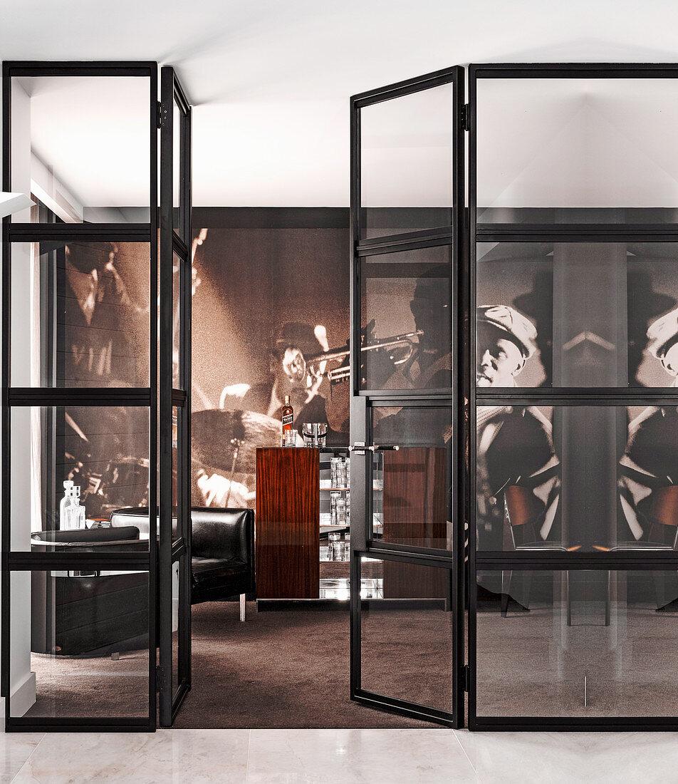 Blick durch Glastür in Hausbar mit Bartheke, Ledersesseln und Desinger-Tapete