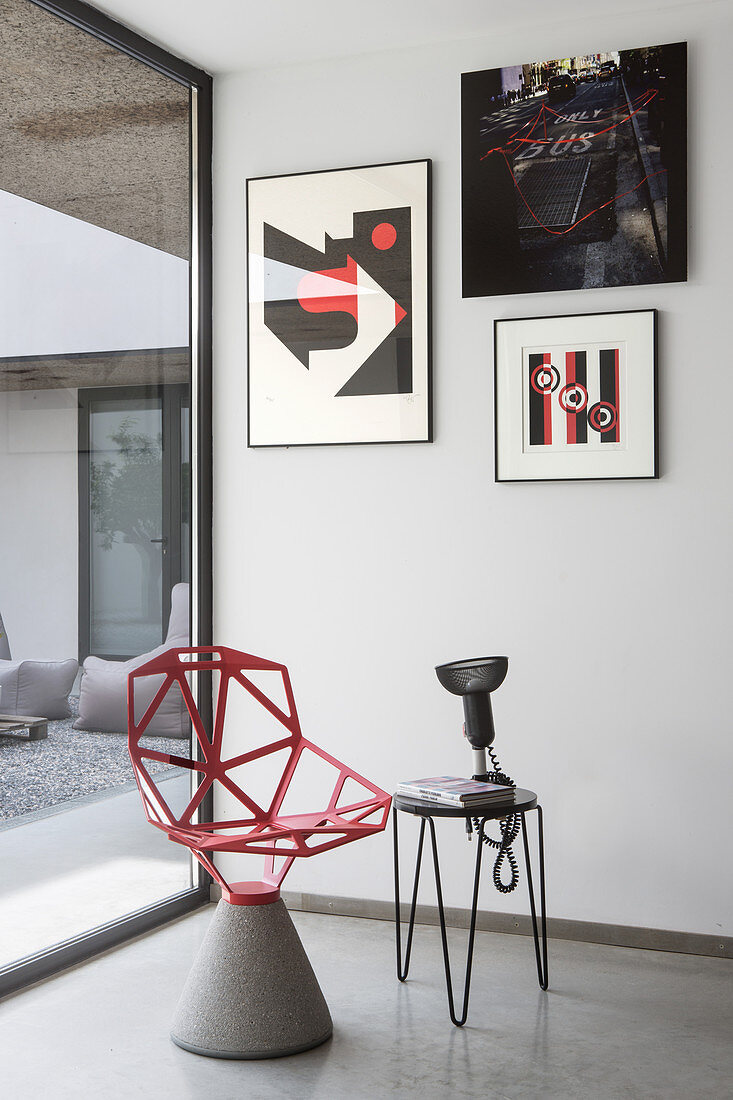Roter, Designerstuhl mit Zementfuß und Beistelltisch unter moderne Kunst