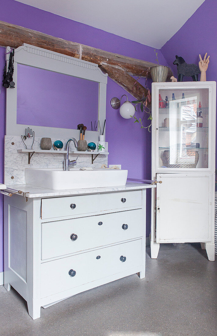 Alte Kommode mit Waschbecken und Schränkchen im violetten Bad