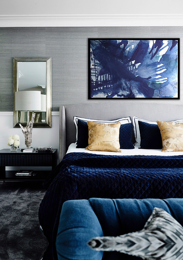 Double bed in the bedroom with blue accessories and wallpaper with metal mesh
