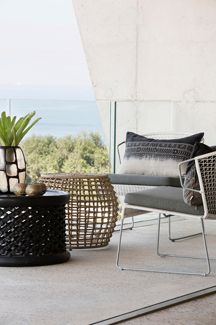 Delicate coffee tables and armchairs on balcony with sea view