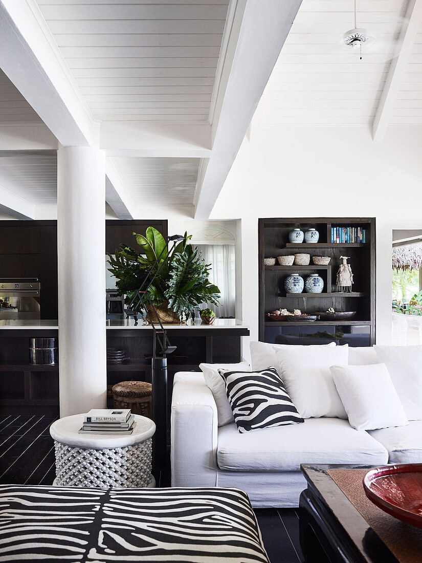 Open living room with white upholstered sofa, pillows and ottoman in zebra look