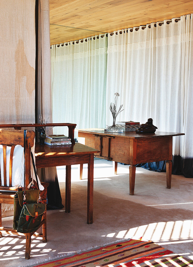 Antik Tisch vor Fenster mit bodenlangen Vorhängen