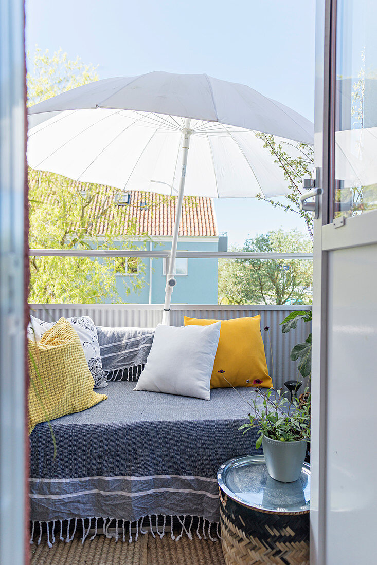 Tagesbett mit Kissen und Sonnenschirm auf dem Balkon