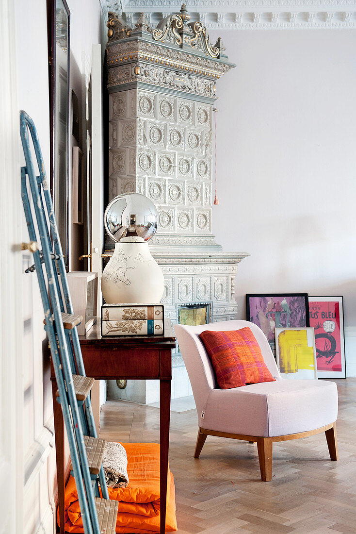Rosafarbener Sessel vor antikem Kachelofen in der Zimmerecke
