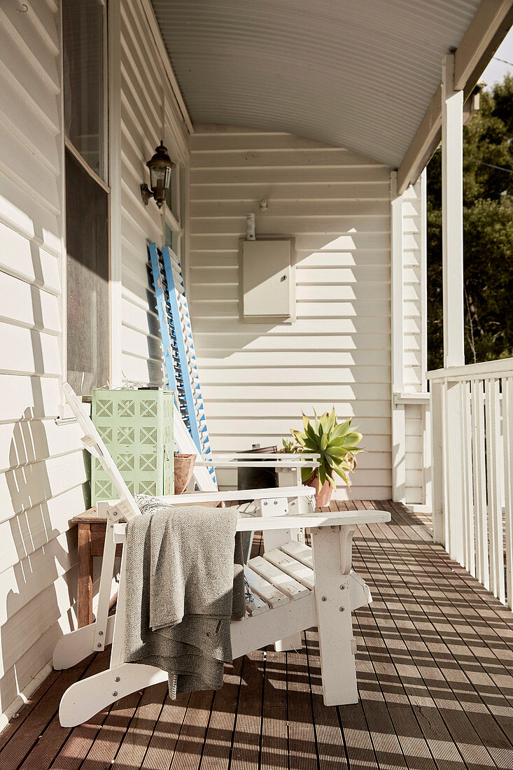 Liegestuhl auf Veranda mit weiß gestrichener Holzverkleidung