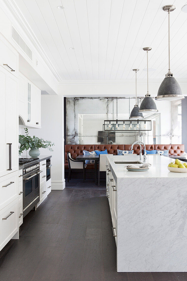 Küchenzeile und Marmor-Kücheninsel unter Pedelleuchten in offenem Wohnraum