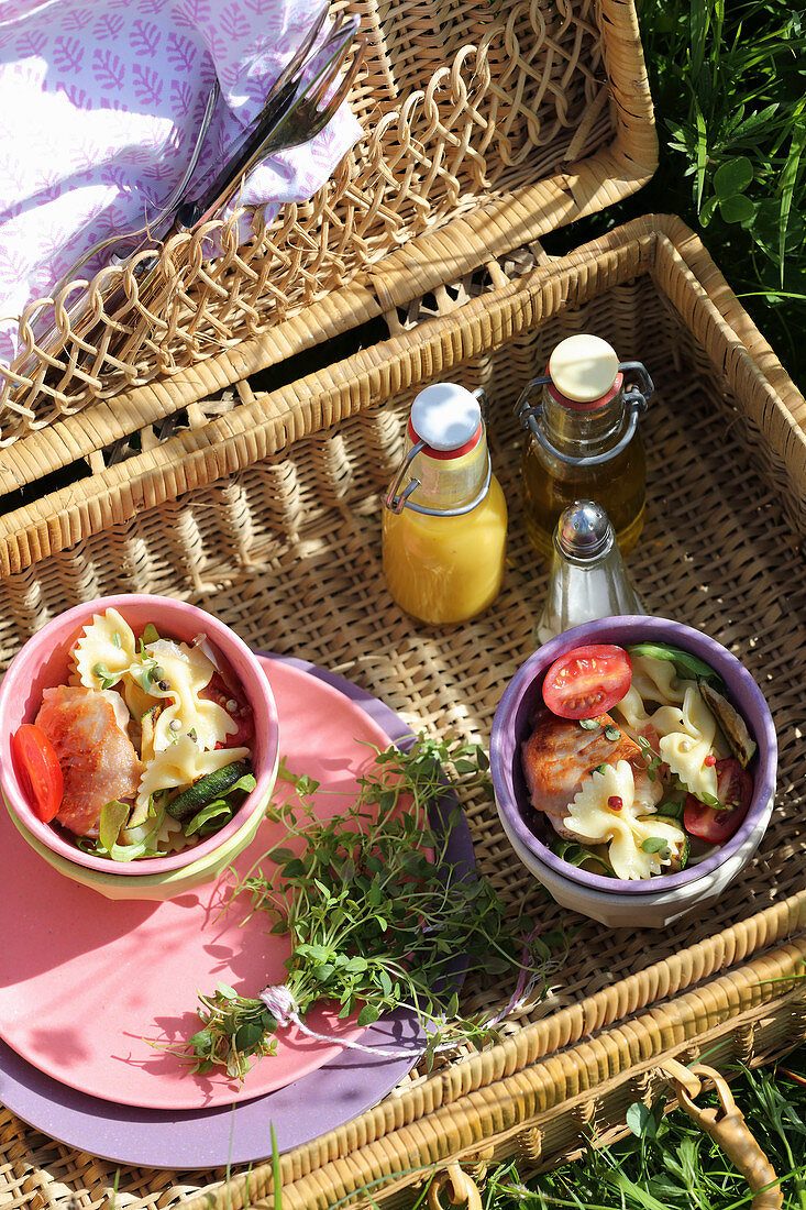 Offener Picknickkorb mit Nudelsalat und kleinen Bügelflaschen