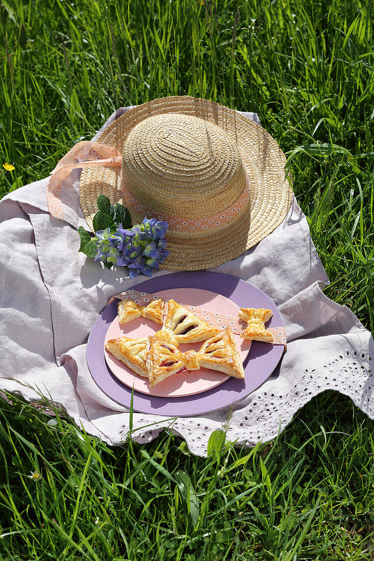 Bow-shaped pastries on purple plate in meadow
