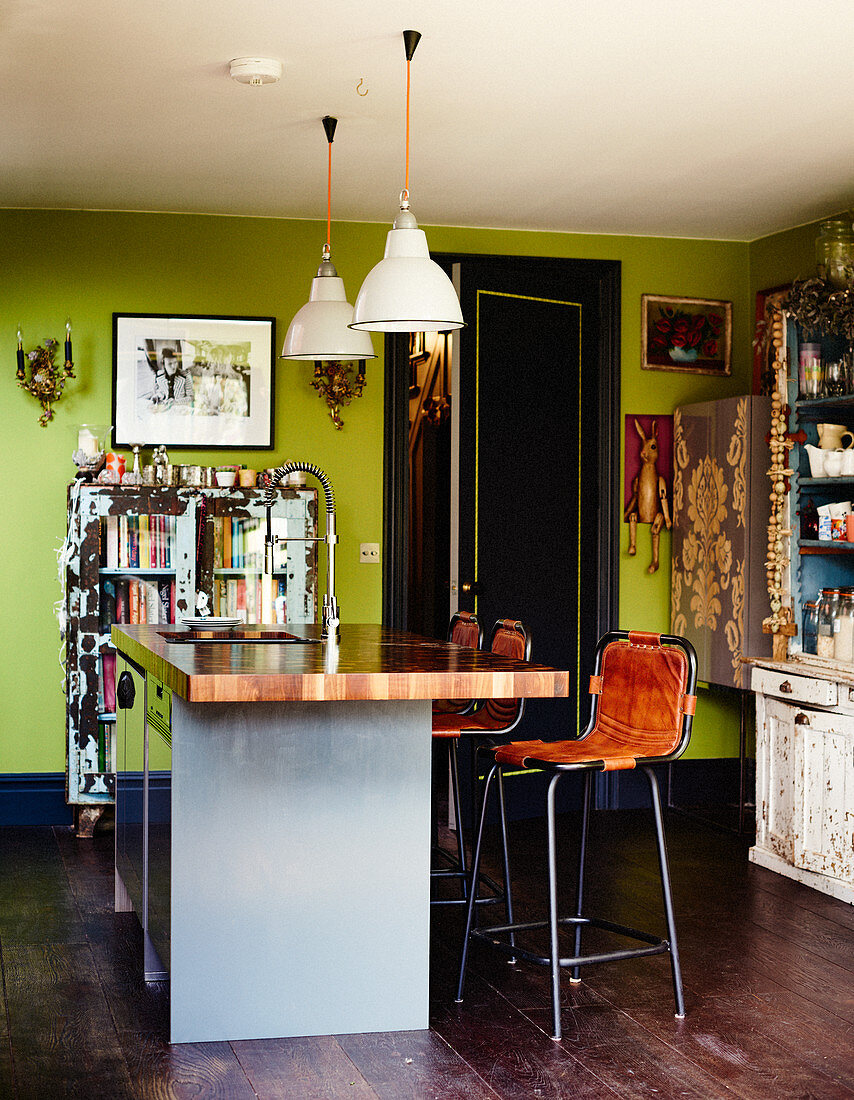 Colourful mixture of files in kitchen-dining room with green walls