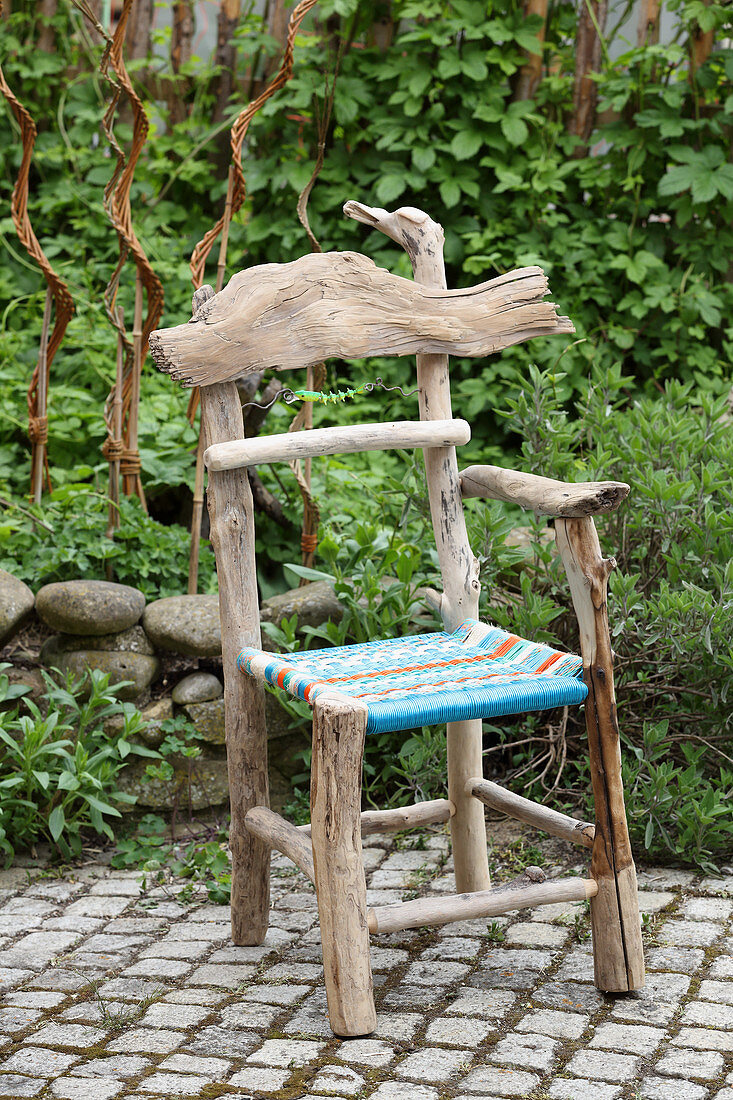 Rustikaler Stuhl aus Treibholz mit bunt gewebter Sitzfläche