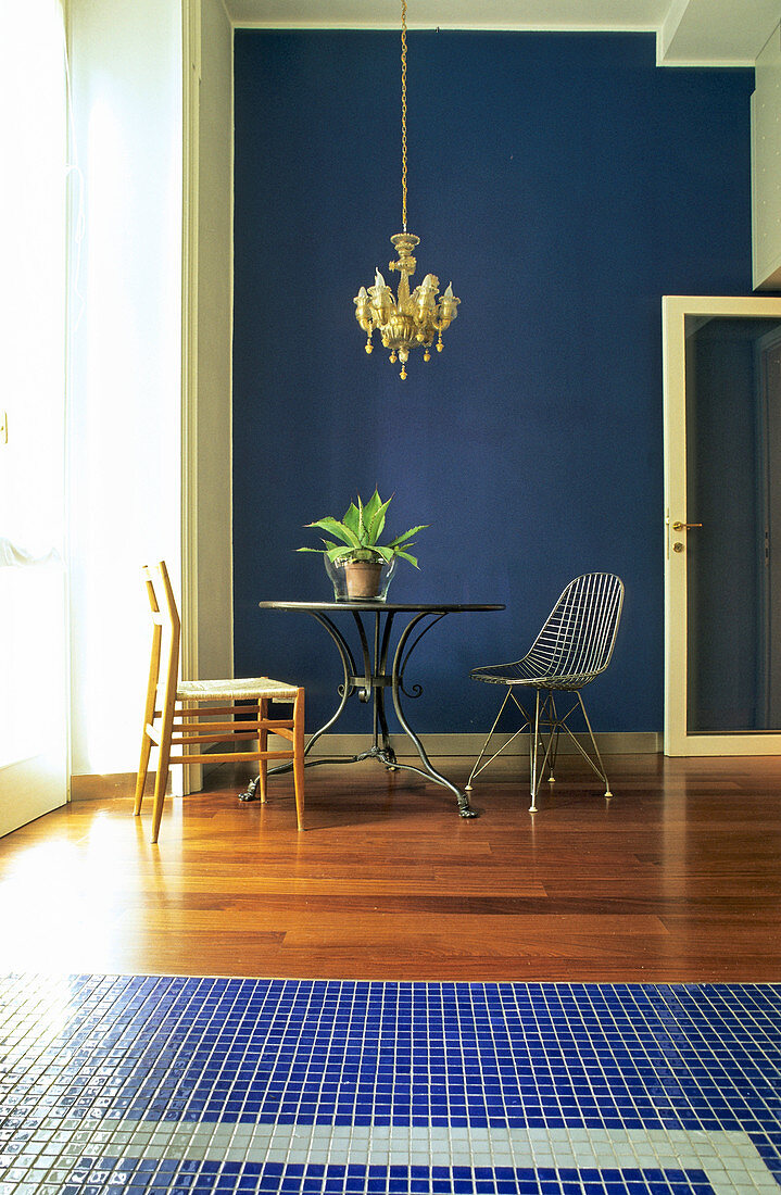 Runder Tisch mit verschiedenen Stühlen vor dunkelblauer Wand