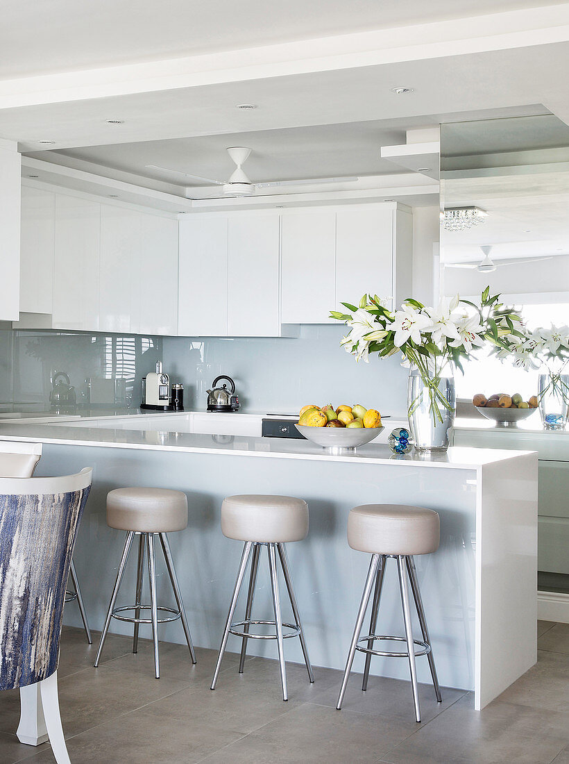 Barstools at island counter with glossy white cabinets