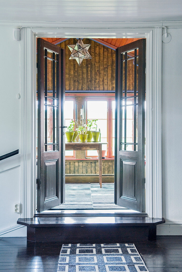 Offene Doppeltür mit Sprossenfenster zum hellen Raum mit Pflanzen