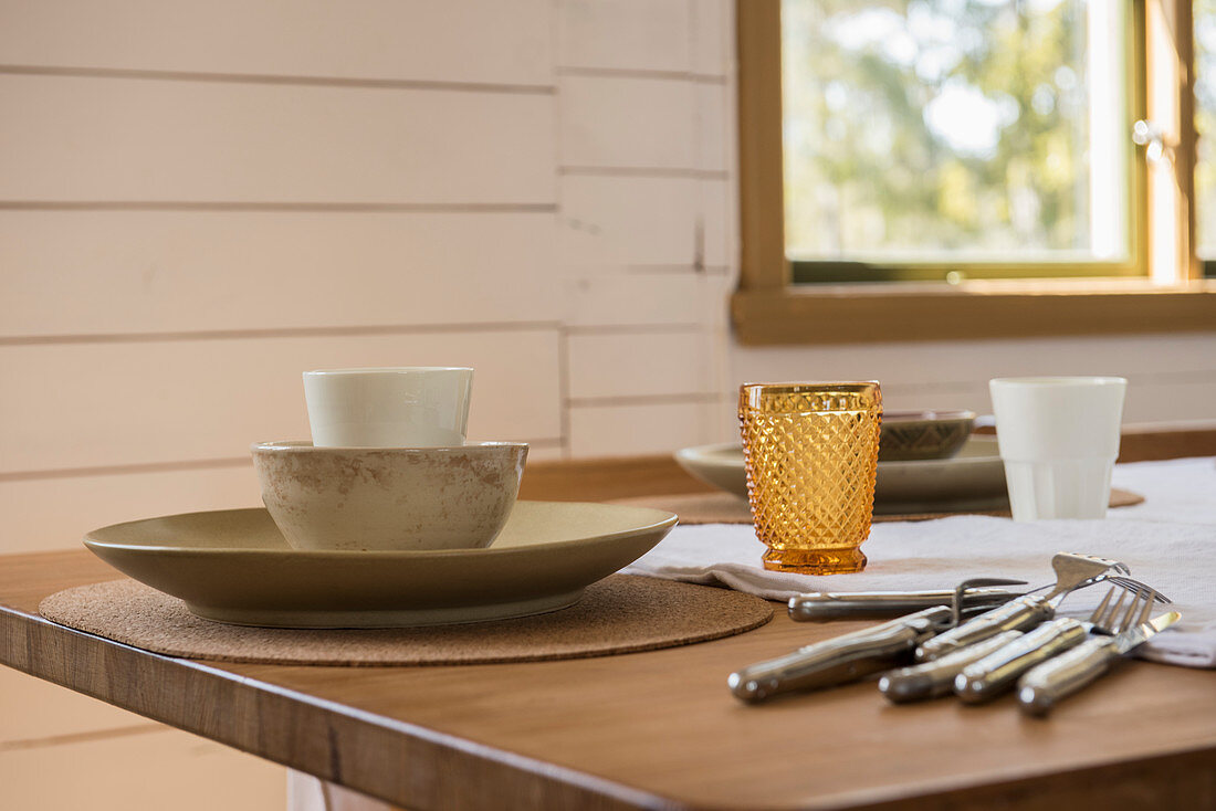 Geschirr, Besteck und Gläser in soften Naturtönen auf dem Tisch