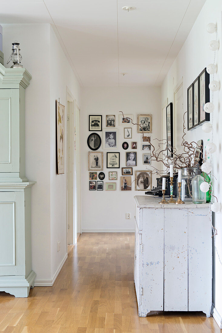 Old cabinet in hallway with gallery of vintage-style pictures