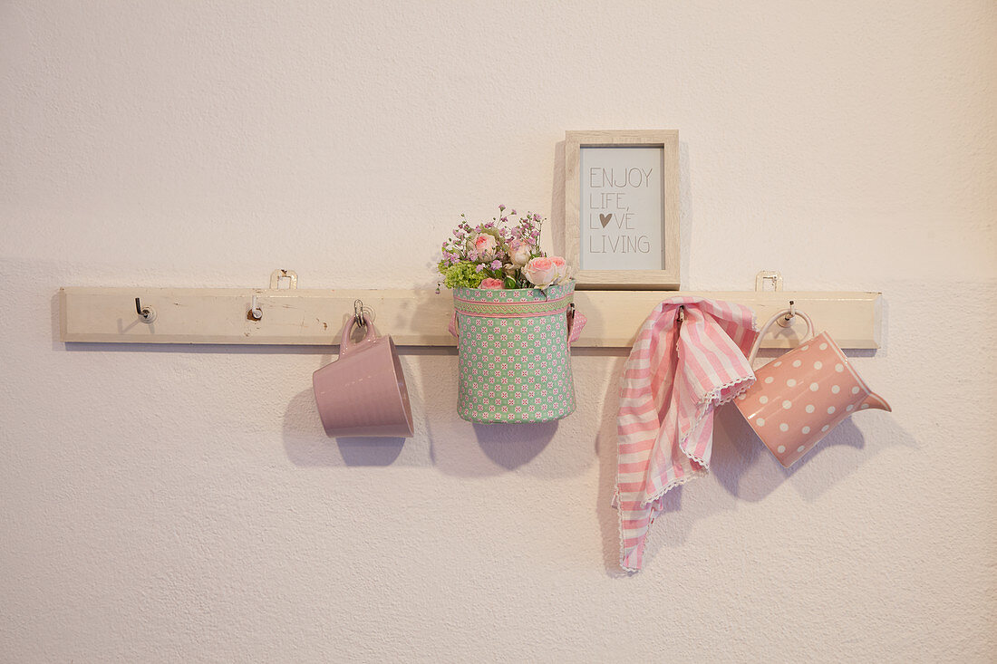 Fabric-covered basket of flowers and crockery hung from peg rack