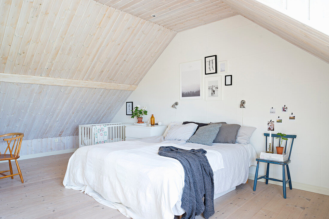 Schlichtes Schlafzimmer unter dem Dach mit verkleideten Wänden