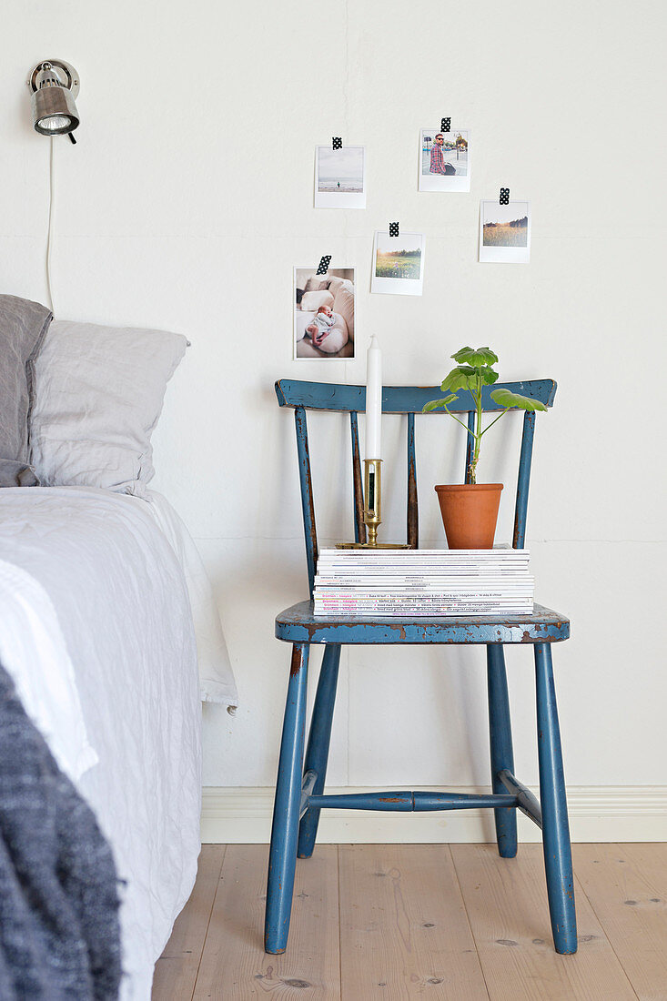 Stacked magazines on old blue chair used as bedside table