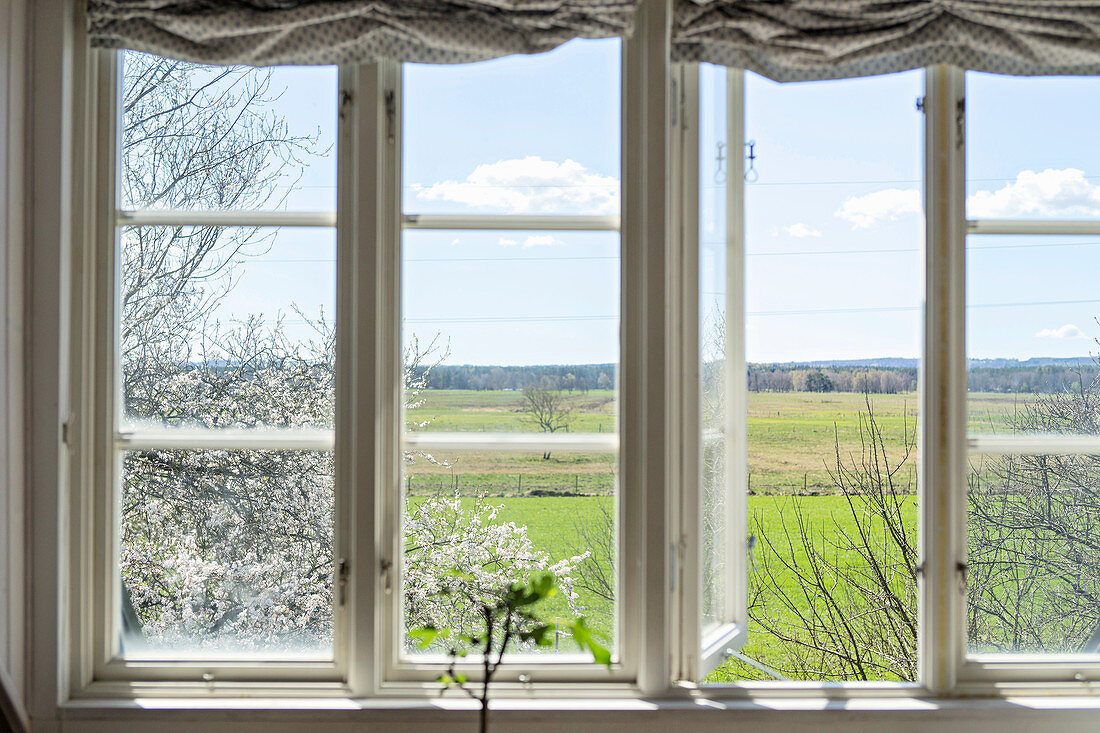 Blick aus dem Fenster auf eine weite Landschaft im Frühling