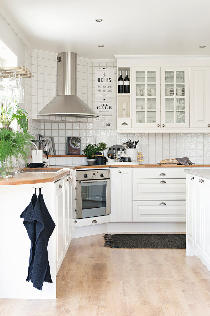 White fitted kitchen with corner cabinets and white wall tiles