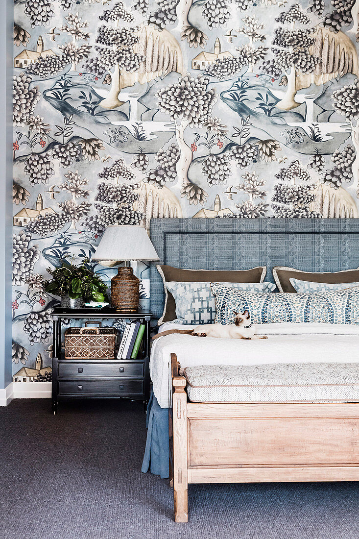 Doppelbett mit Bettkopfteil und Nachttisch vor silber-grau tapezierter Wand