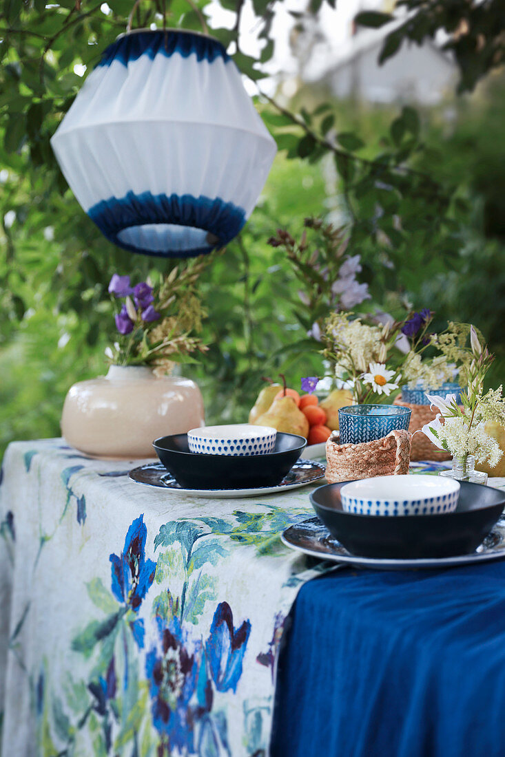 Gedeckter Tisch in Blautönen unter weiß-blauer Laterne im Garten