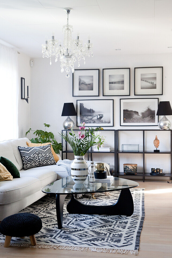 White sofa, glass coffee table, low shelves and gallery of pictures in living room