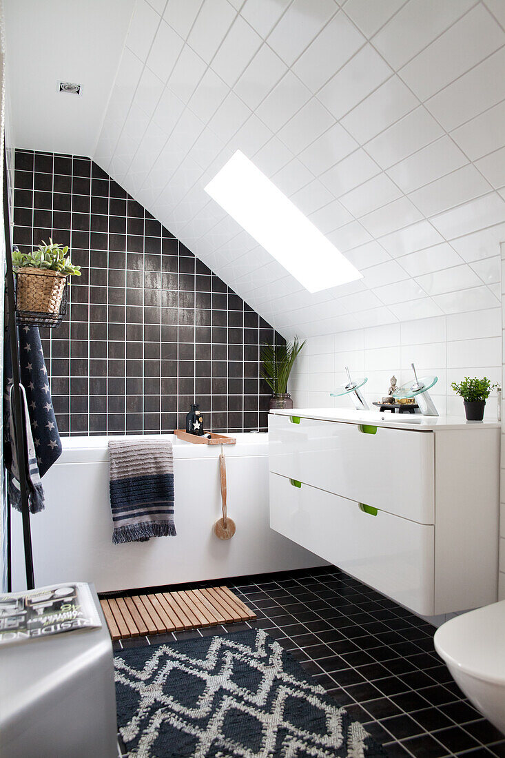 Washstand and bathtub in black-and-white bathroom with skylight