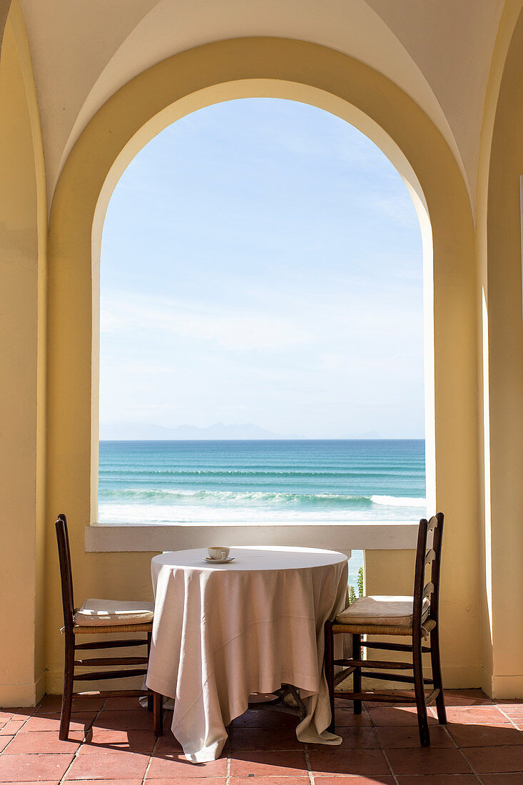 Tisch und zwei Stühle in der Loggia mit pittoreskem Meerpanorama