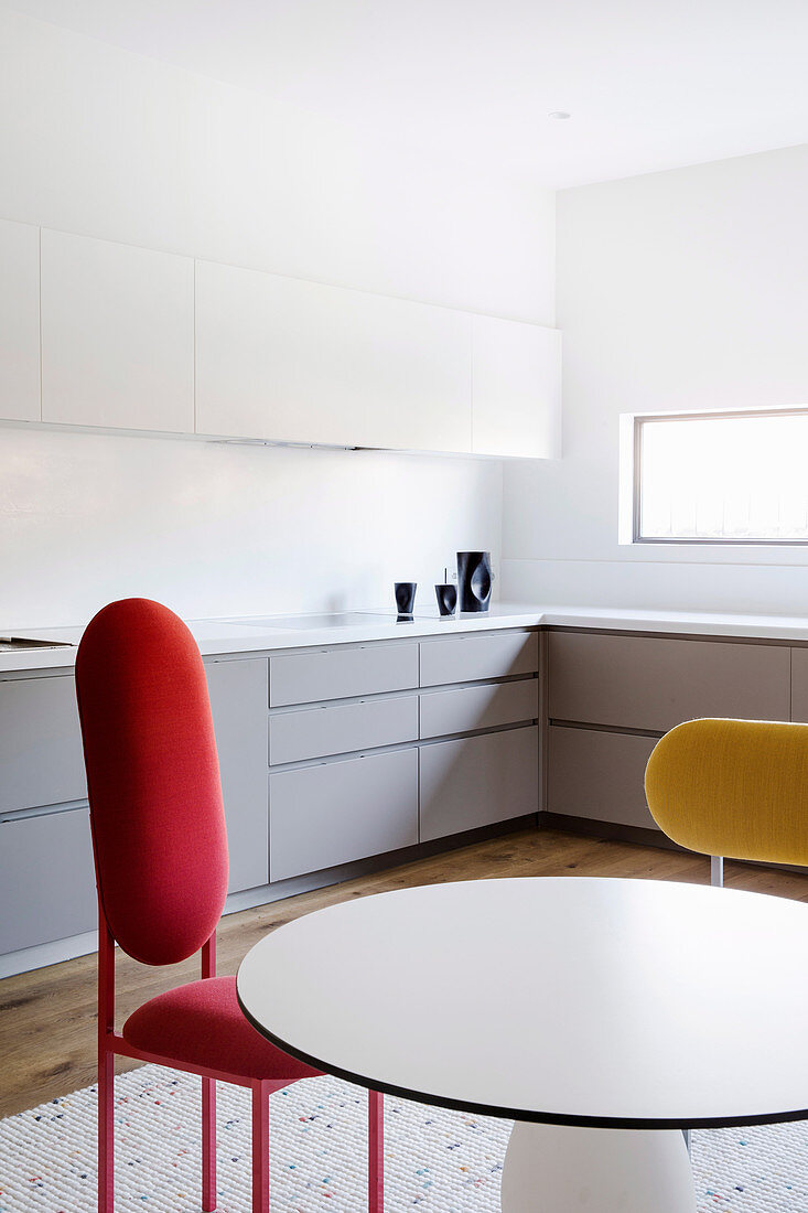 Runder Tisch und Designerstühle in weißer Einbauküche