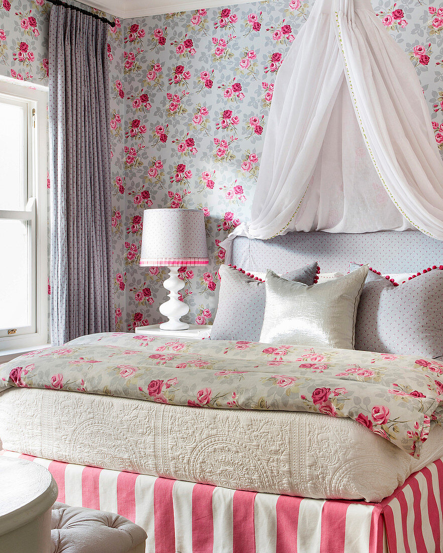 Verspieltes Schlafzimmer mit Rosenmustertapete und Bett mit Betthimmel