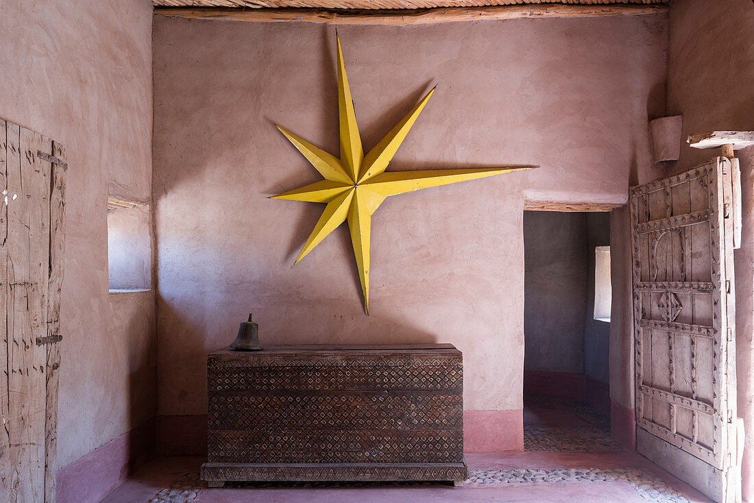Gelber Stern an der Wand über einer alten Truhe im Lehmhaus