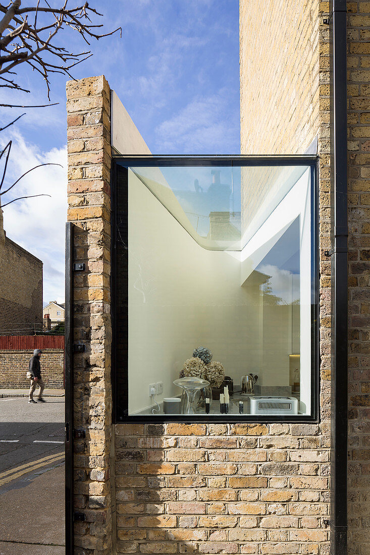 Kitchen window of modernised brick house below blue sky