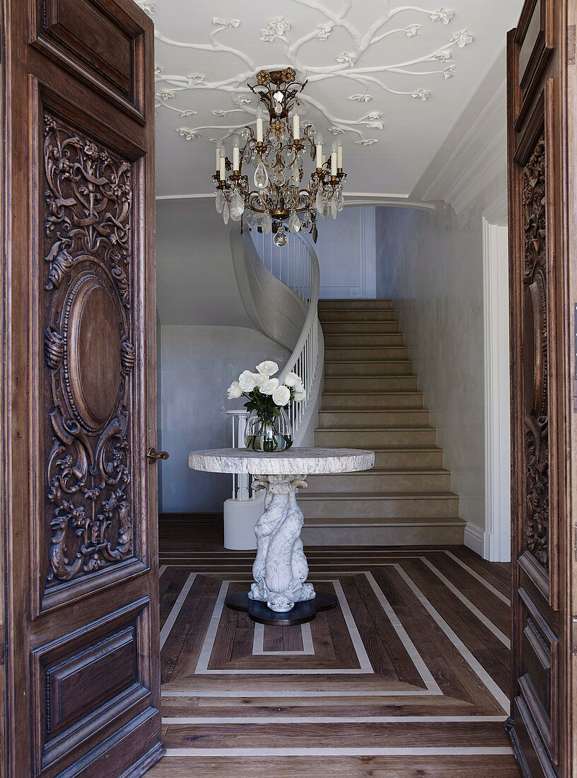 Elegante Eingangstür mit Holzschnitzerei aus dem 19. Jahrhundert, runder Marmortisch in der Eingangshalle