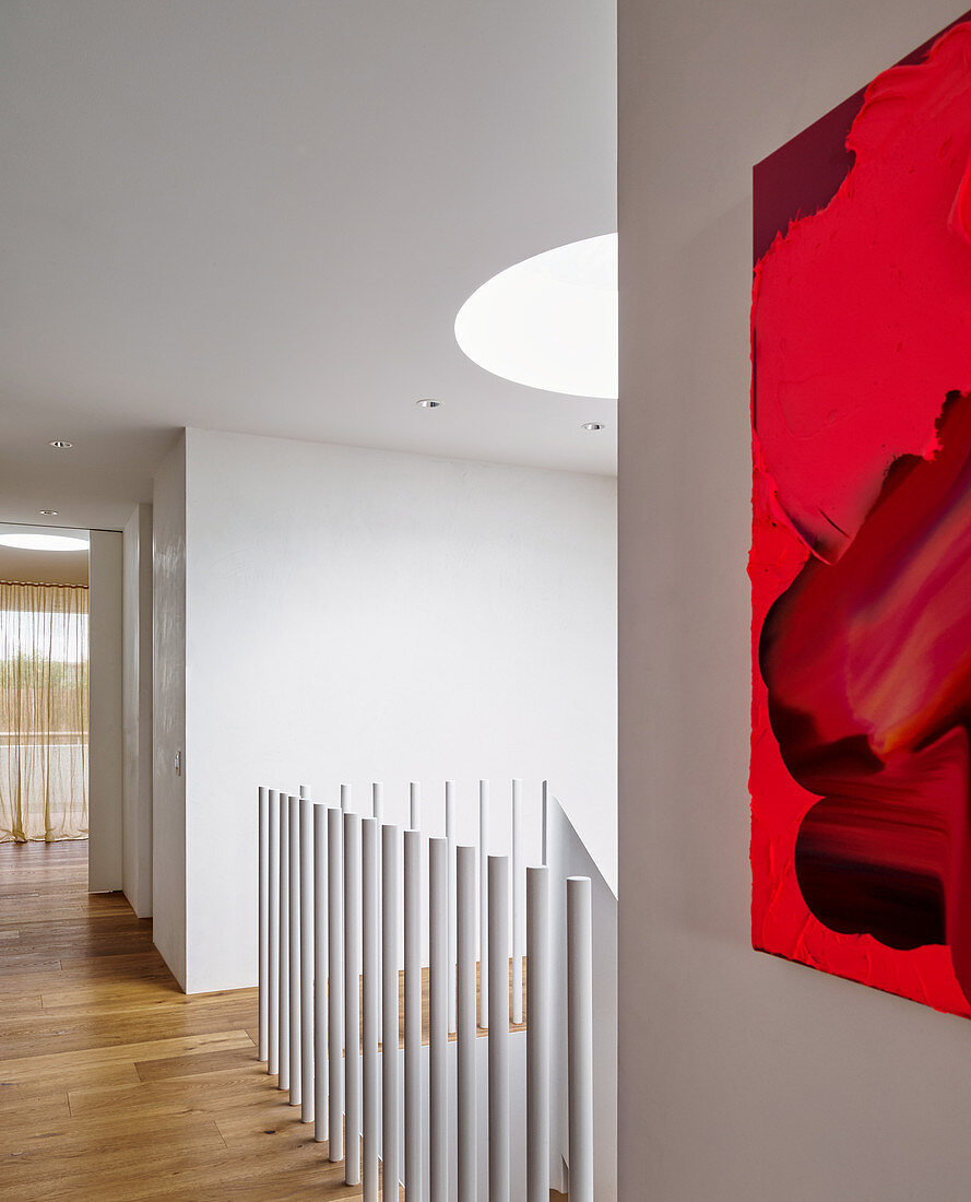 Large-sized artwork in shades of red on a white wall in the hallway