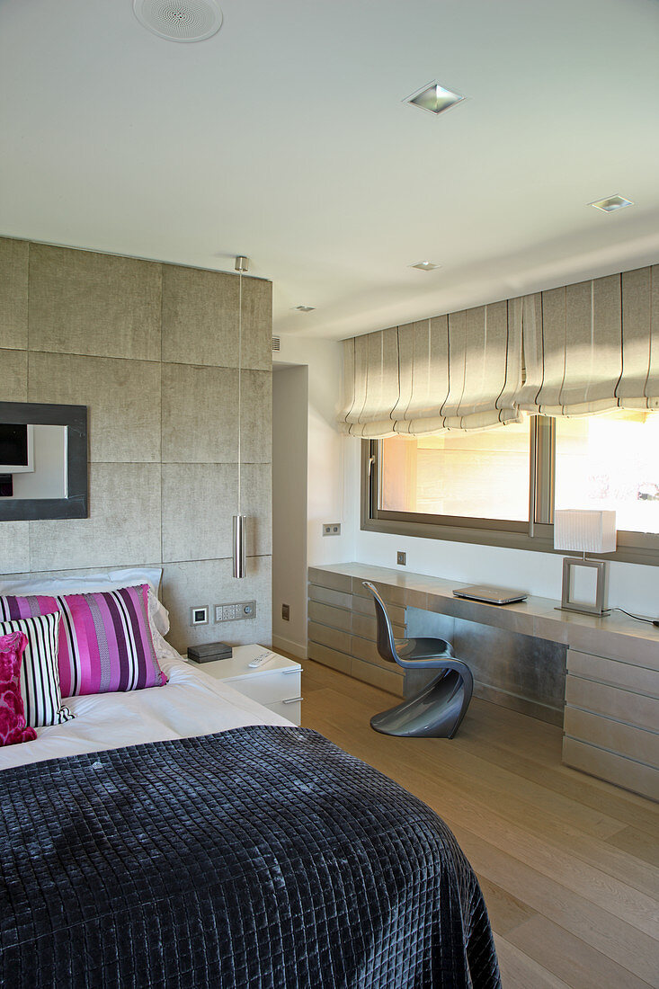 Modern bedroom in beige with long desk below windows
