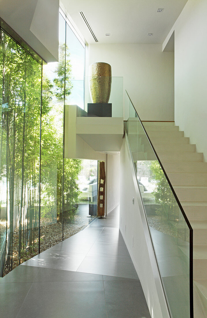 Treppe mit Glasbalustrade im Flur mit Glaswand zum Bambusgarten