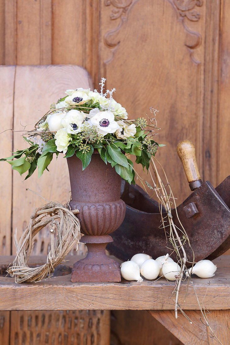 Bouquet of anemones, carnations and ivy in rusty urn