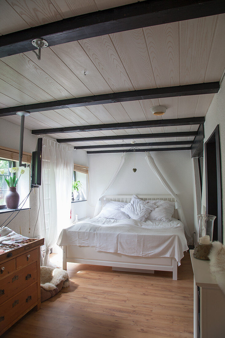 White bed with white bed linen in converted barn