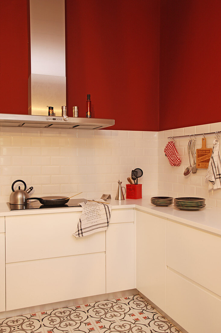 Moderne weiße Küche mit roter Wand und gemustertem Boden