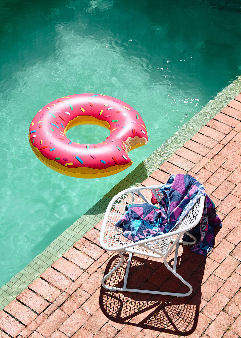 Pool with swim hoops, chair with bath towel on the edge